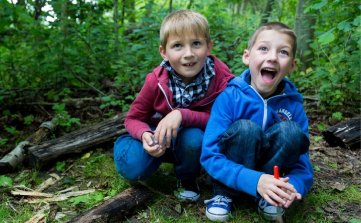 Two children kneeling down during bug hunting in a woodland